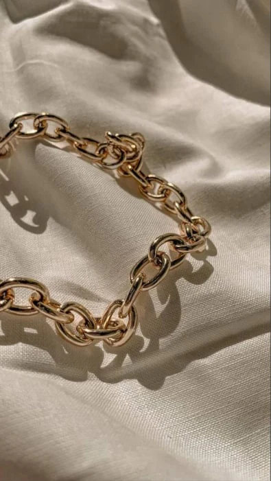 A gold chain bracelet on linen